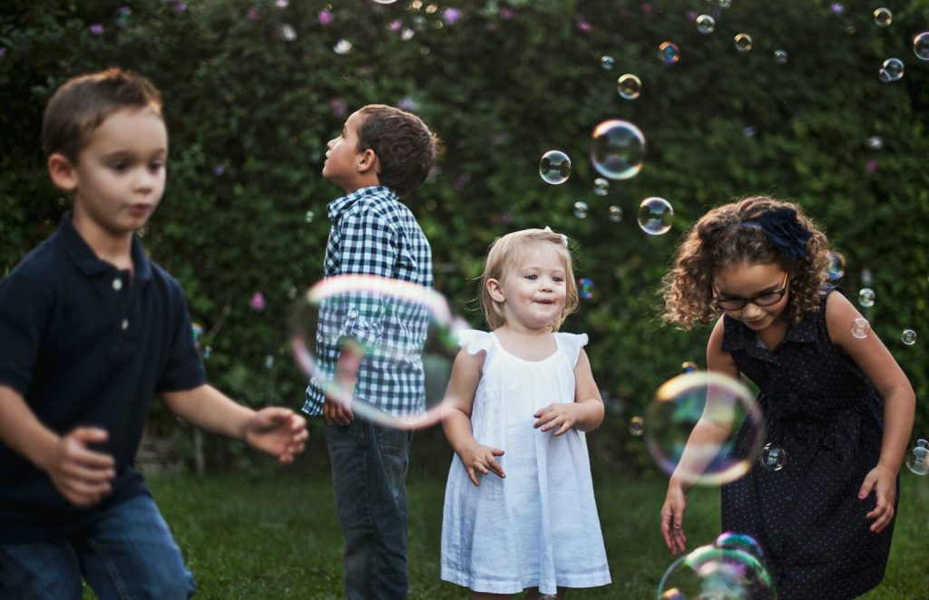 Children surrounded by bubbles outdoors